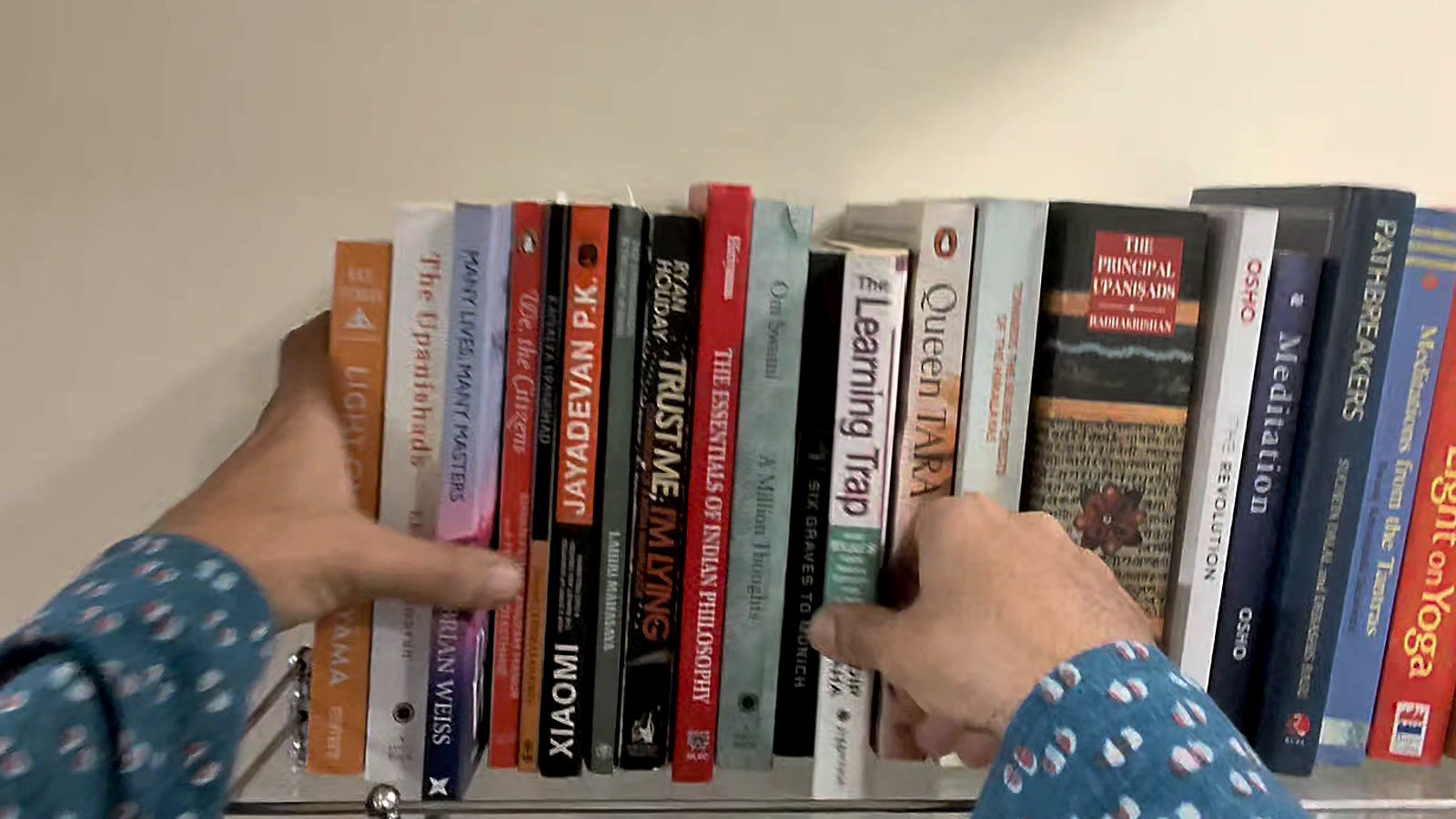 A hand pulling one book from a full shelf at Sylvaris.